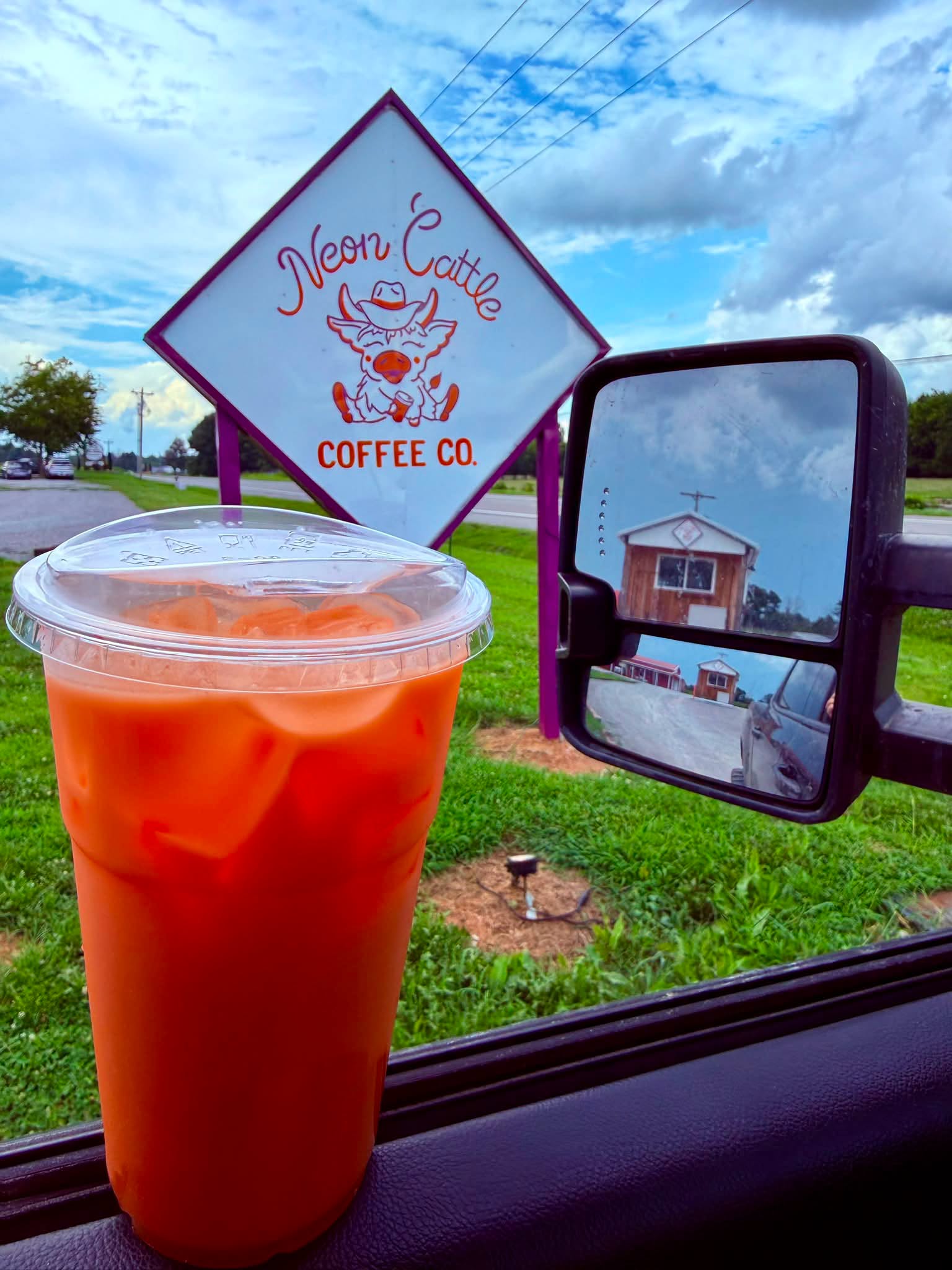 Iced orange drink in a truck window across from the Neon Cattle sign