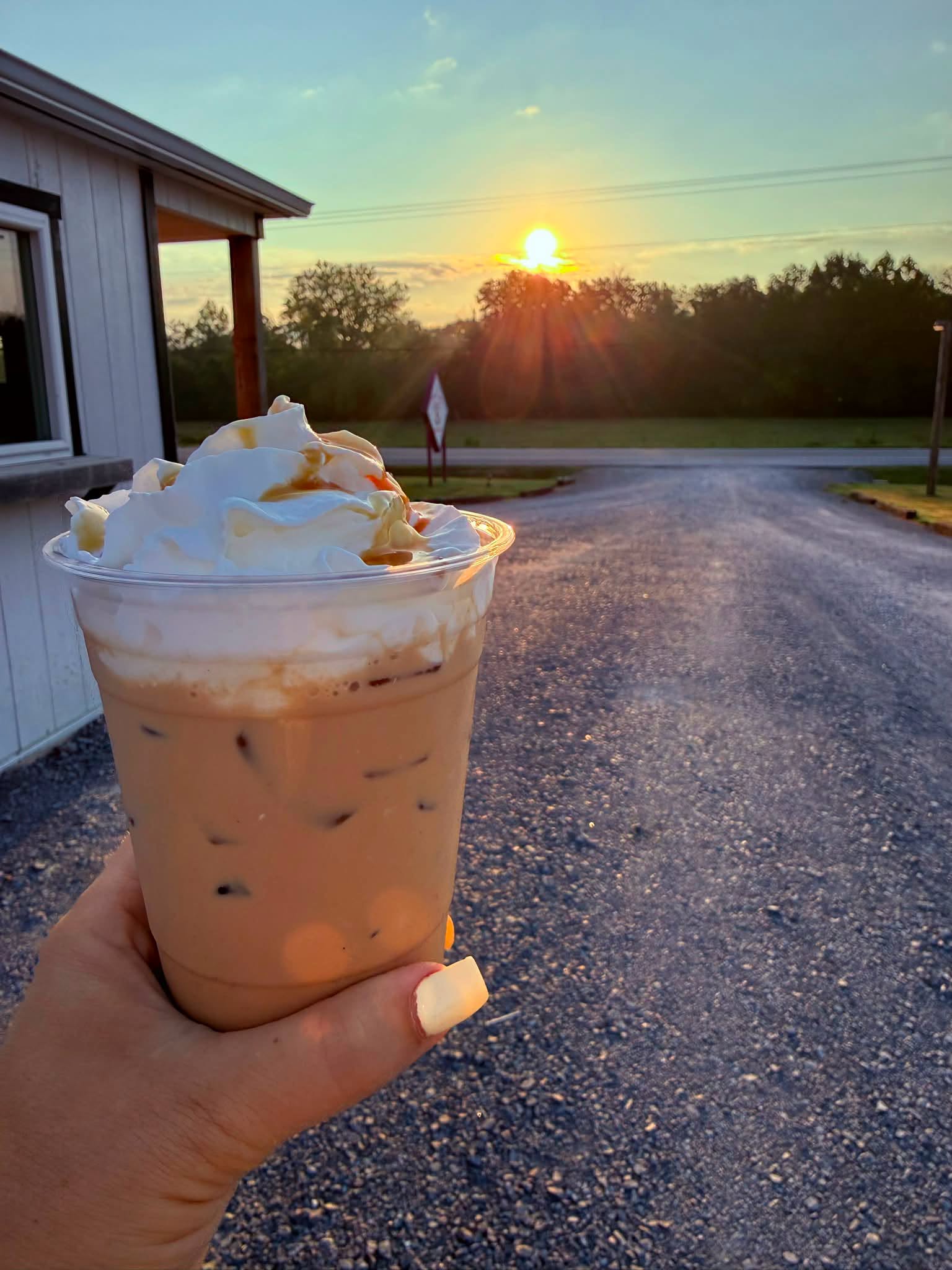 Iced coffee with whipped cream and caramel at sunrise outside the stand