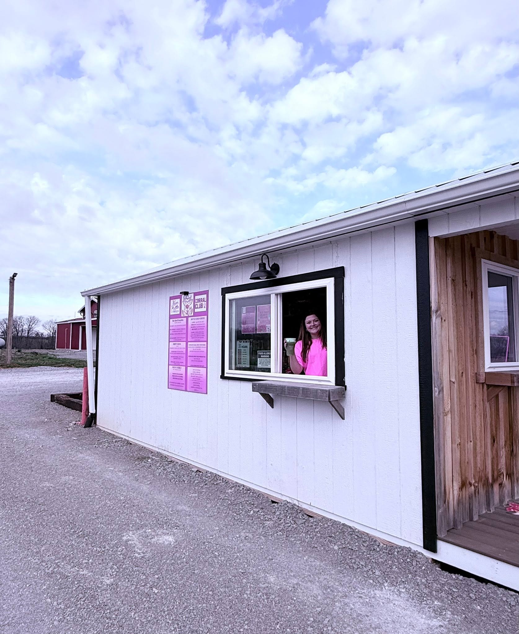 Barista holding up a drink at the Neon Cattle drive-thru window